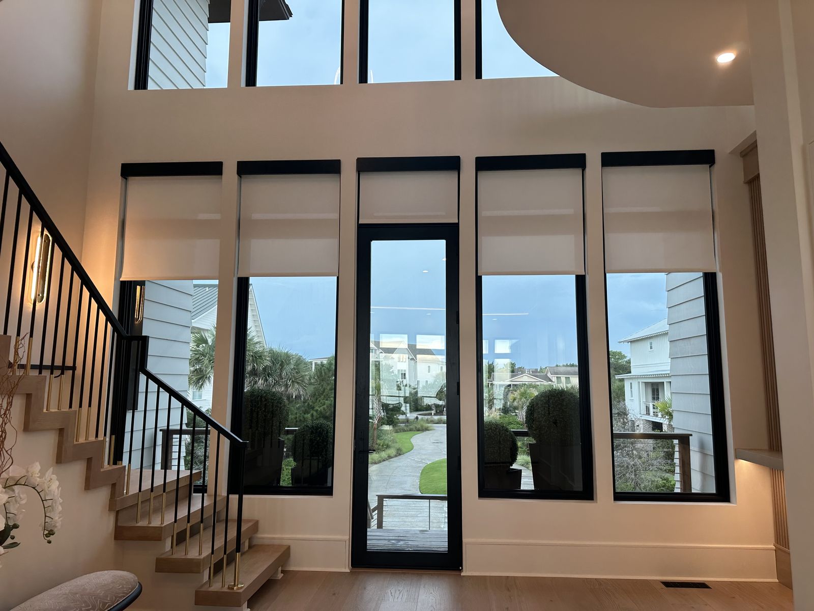 Motorized roller shades on tall windows in a two-story foyer